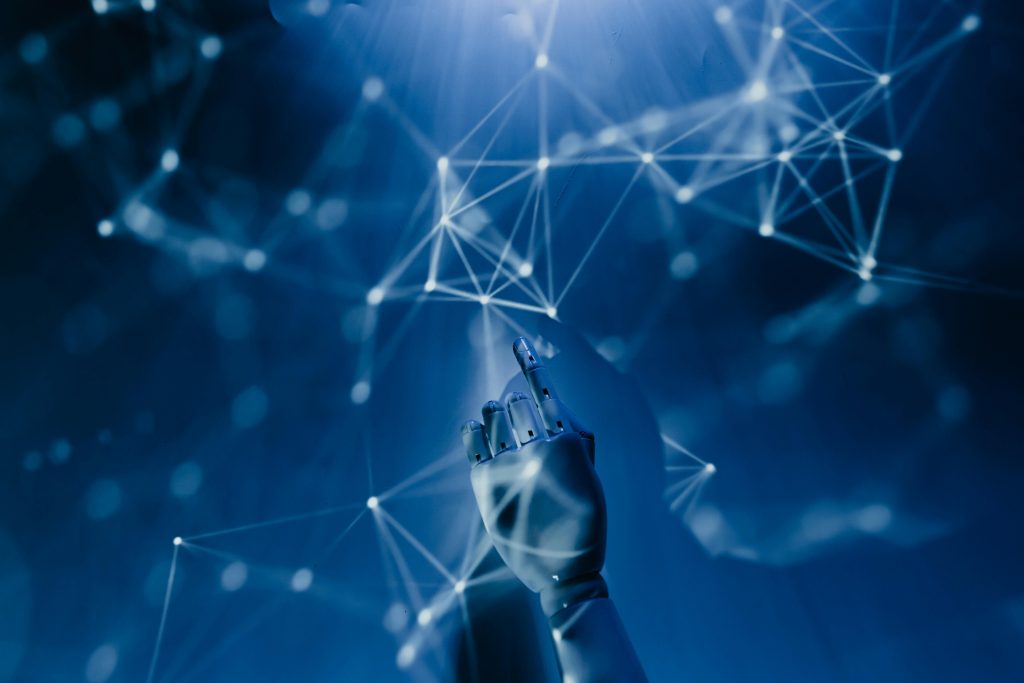 pexels-photo-8386440-8386440 A robotic hand reaching into a digital network on a blue background, symbolizing AI technology.